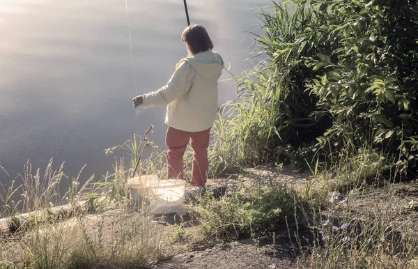 Žena lovící na břehu krásného jezera. — Stock fotografie