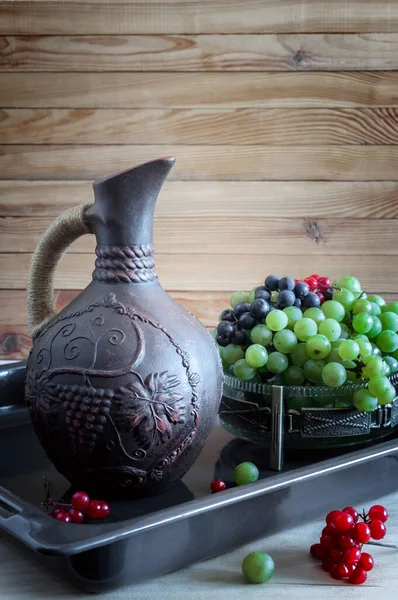 Druvor och vin i en kanna på bordet — Stockfoto
