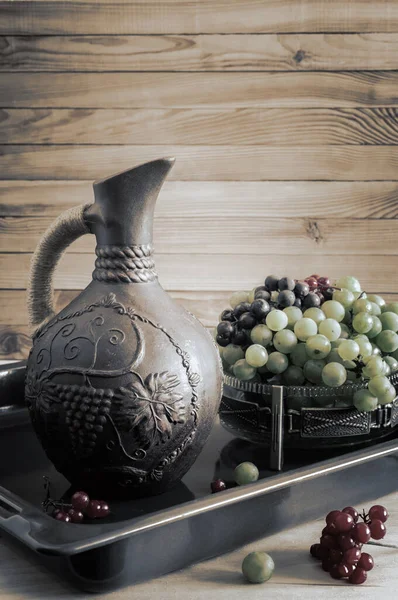 Uvas y vino en una jarra sobre la mesa —  Fotos de Stock