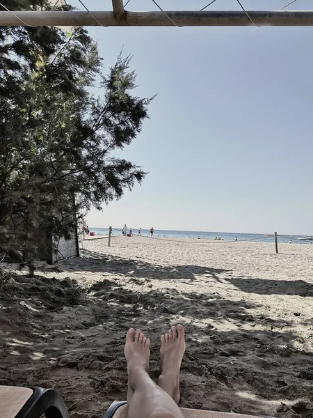 Uitzicht op het strand vanaf een chaise longue met vakantiegangers. — Stockfoto