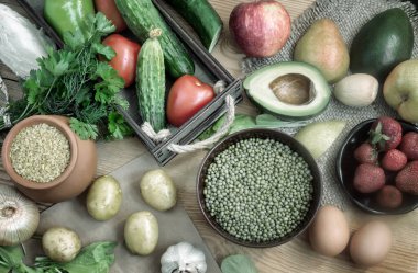 Tahta masadaki çeşitli organik gıda ürünleri: meyve, sebze, yumurta, bulgur gevreği, lahanalı fasulye. Sağlıklı beslenme kavramı. Yukarıdan görünüşü