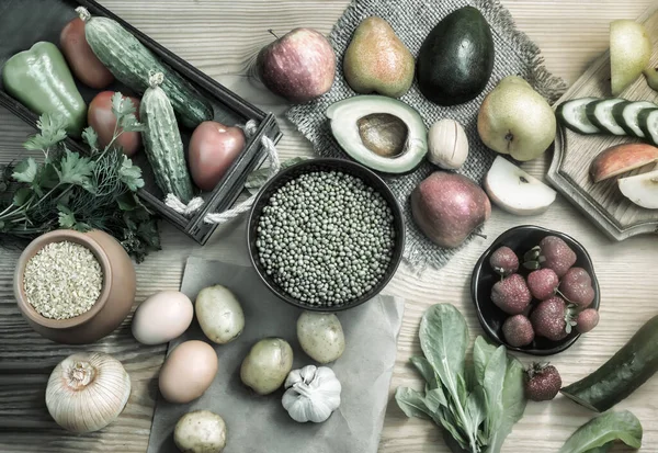 A variety of organic food items on the wooden table: fruits, vegetables, eggs, bulgur cereals, beans with sprouts. The concept of healthy eating. The view from the top