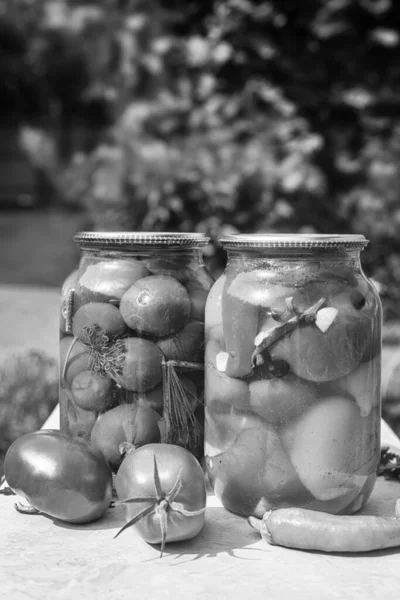 Canned tomatoes and peppers in glass jars. — Stock Photo, Image