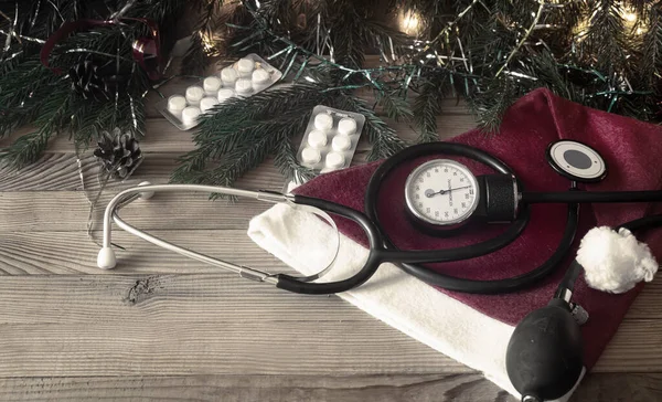 Vánoce v medicíně: stetoskop, pilulky a vánoční ozdoby, věnce, čepice Santa Claus. — Stock fotografie