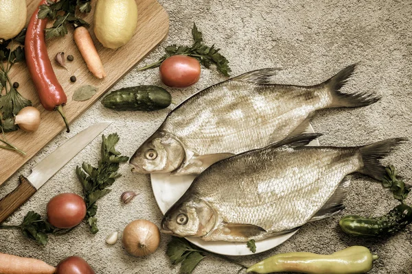 皿の上に2つの大きな鯛があります 近くにはこの川魚を調理するための野菜やスパイスがあります コピースペース付きのトップビュー — ストック写真