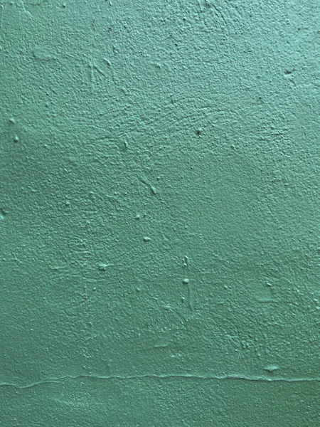 Freshly painted wall in cyan teal color with cracked line on the bottom and uneven surface in the interior design
