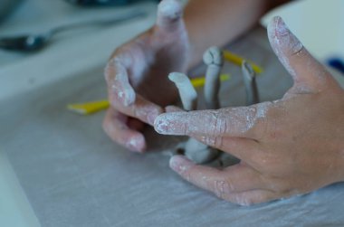 Beyaz çömlek kil projesinde çalışan küçük parmaklar