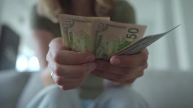 Amerikan dolarlarını elinde tutan ve sayan bir kadın. Kişisel finans ve tasarruf kavramı