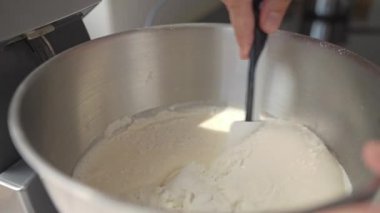 Metal kaseye kalın kek hamuru karıştırmak için spatula kullanan bir el. Ev yapımı pişirme kavramı