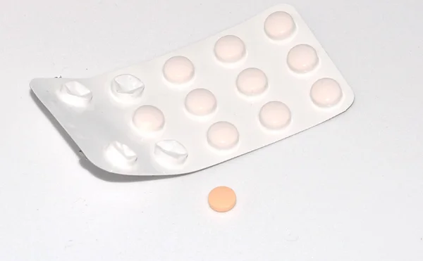 Single orange pill in front of a blister pack — Stock Photo, Image