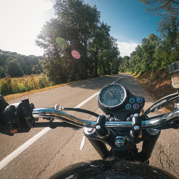 曲がりくねったターマック道路でスピードメーター付きの古い黒いバイクに乗る — ストック写真