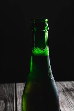 Siyah arka planda dolu yeşil bira şişesi.