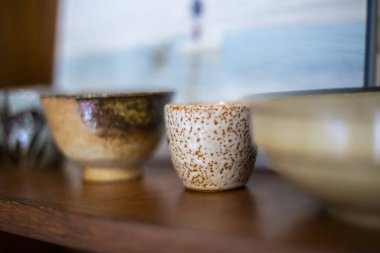 Ahşap bir raftaki seramik kaplar bir sırada dekorasyon malzemesi olarak