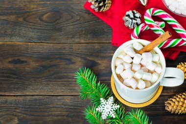 Fincan kakao marshmallows, lolipop, köknar ve çam kozalakları, Noel ağacı dalı ve kahverengi ahşap zemin üzerinde kar tanesi