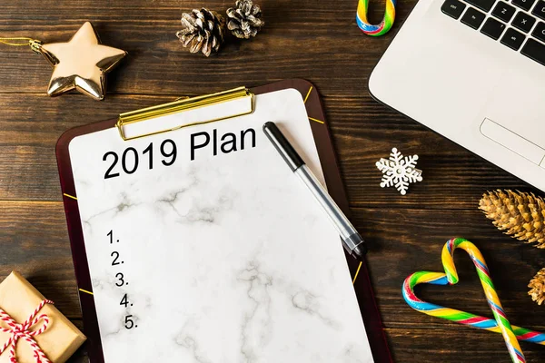 2019 yeni yıl kararları, hedefleri ve planları bir Pano için anımsatıcıları ve süsleri çam kozalakları kahverengi ahşap arka plan, kopya alanı üzerinde altın yıldız, şeker kamışı, beyaz bir dizüstü bilgisayar üzerinde yazılı