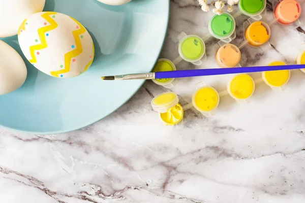 El concepto de Pascua - la puesta plana del plato azul con los huevos y los tintes de colores con el pincel para los huevos tradicionales de la pintura sobre la mesa de mármol — Foto de Stock