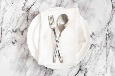Düz yatıyordu çatal, çatal ve bıçak bir rustik peçete üzerinde mermer bir masa üzerinde boş beyaz bir plaka üzerinde yalan. Restoranda akşam yemeği için yer.