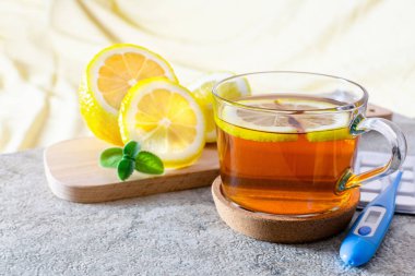 Bir ahşap tahta ve sıcaklık ölçmek için termometre üzerinde hastalığın tedavisi için limon ve nane ile sıcak çay bir fincan, haplar. Kışın veya sonbahar mevsiminde soğuk algınlığı için sağlıklı içecek