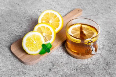Bir fincan sıcak çay limon ve nane bir dilim taştan yapılmış bir masa üzerinde ahşap kesme tahtası üzerinde hastalığın tedavisi için. Kışın veya sonbahar mevsiminde soğuk algınlığı için sıcak ve sağlıklı bir içecek.