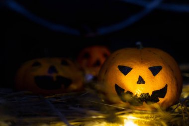 Üç komik veya kızgın kabaklar Jack Lantern başı saman, sonbahar sarı yaprakları ve örümcek ağları arka plan karşı. Koyu ahşap tahta üzerinde birbiri ardına biryüz, kopya alanı