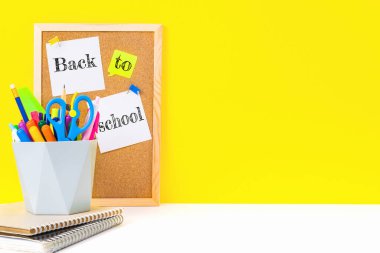 Üzerinde bayraklarla yapıştırılmış yapışkan çarşaflar ve ofis malzemeleriyle düzenleyici olan notlar için mantar pano. Kopya alanı ile sarı arkaplan hakkında eğitim ve bilgi kavramı.