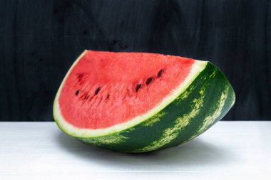 İştah açıcı olgun karpuz parçası beyaz bir masada tebeşir karatahtasının arka planına karşı. Mevsimlik tatlı tropikal meyve kırmızısı yeşil renk, vitamin, yaz zamanı, sağlıklı tatlı.