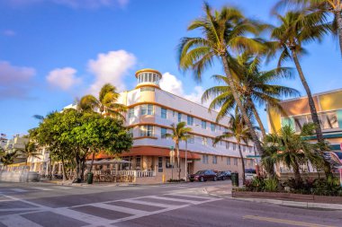 Palm ağaçları ve araba ile günbatımı okyanus sürücü sahnesi, Miami Plajı. Ocean Drive 'da gün batımında Art Deco tarzı oteller ve restoranlar, onun gece hayatı için dünyaca ünlü hedef.