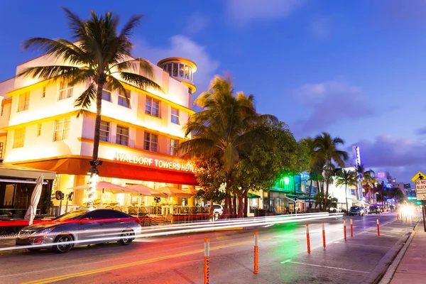 Ocean Drive scene at sunset with palm trees and cars passing by, Miami beach. Art Deco style hotels and restaurants at sunset on Ocean Drive, world famous destination for it\'s nightlife,.