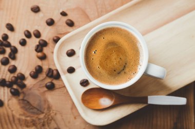 Kahve fincanı bir ahşap tepsi bir tahta kaşık ve kahve çekirdekleri ile görev yaptı. Üstten görünüm, düz yatıyordu