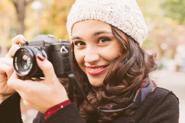 秋に市内のレトロなカメラで写真を撮るウール キャップを持つ若い美しい女性 — ストック写真
