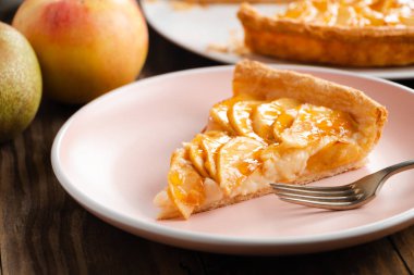 Rustik ahşap arka plan üzerinde pembe bir tabak üzerinde doldurma muhallebi ile ev yapımı elmalı turta tart kısmını