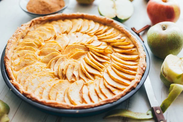 Freshly baked apple pie tart with custard filling on a rustic white wooden background