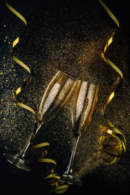 İki kadeh şampanya altın konfeti, parlak ve karanlık bir arka plan üzerinde serpantin toasting. Düz yatıyordu. Gece kutlama kavramının