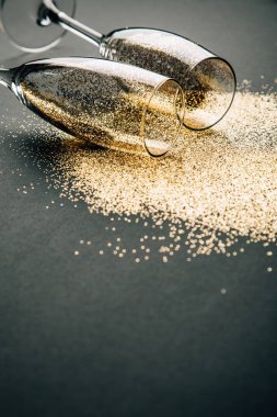 İki kadeh şampanya altın glitter karanlık bir arka plan üzerinde yalan ile toasting. Gece kutlama kavramının