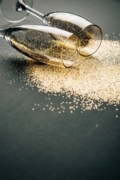 İki kadeh şampanya altın glitter karanlık bir arka plan üzerinde yalan ile toasting. Gece kutlama kavramının