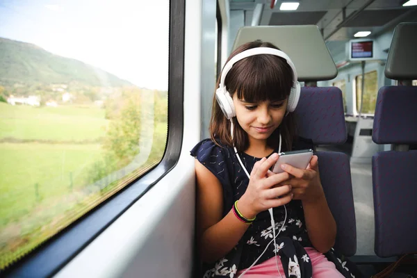 Счастливая Маленькая Девочка Наушниками Используя Свой Смартфон Время Путешествия Поезде — стоковое фото
