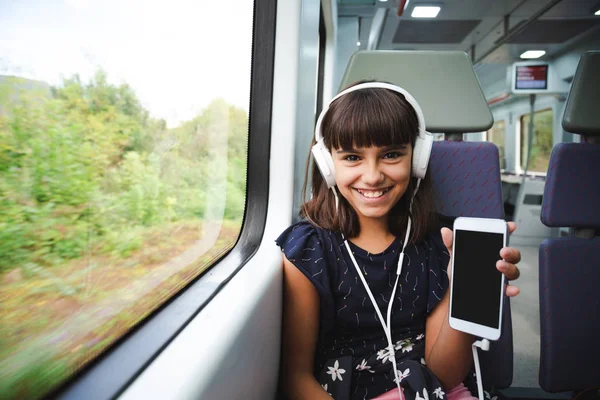 Joyeux Petite Fille Avec Des Écouteurs Montrant Caméra Son Téléphone — Photo