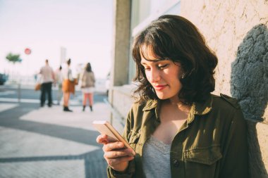 Yeşil ceket cep telefonu sokakta günbatımında kullanarak olan güzel kadın
