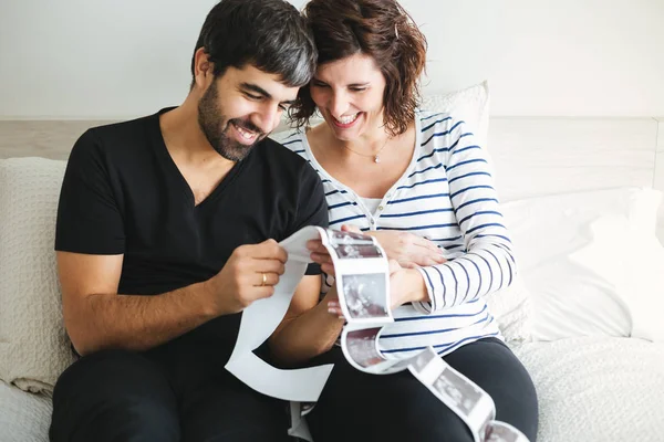 Happy Excited Pregnant Couple Looking Ultrasound Images Baby Sitting Bed — Stock Photo, Image