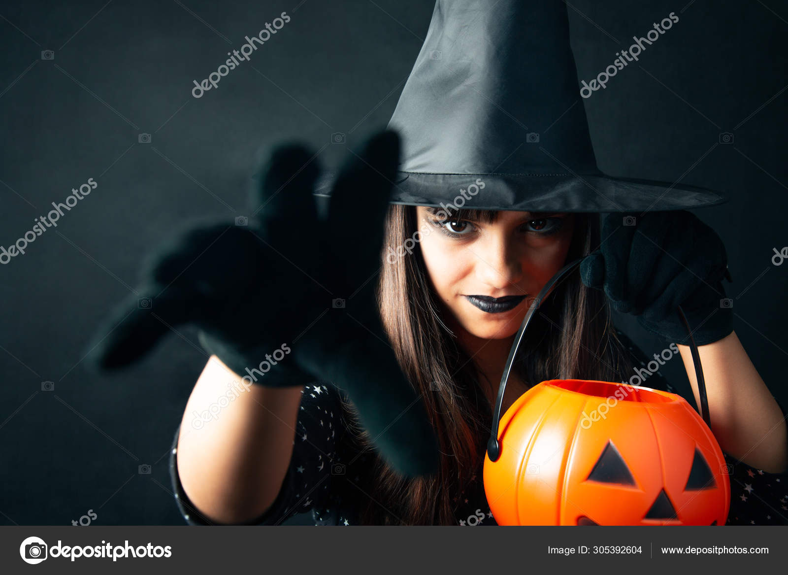 Uma Jovem Bruxa Bonita Em Um Chapéu Cônico Segura Uma Abóbora De Halloween  Em Suas Mãos E Faz Um Feitiço Com Sua Mão. Foto Royalty Free, Gravuras,  Imagens e Banco de fotografias.