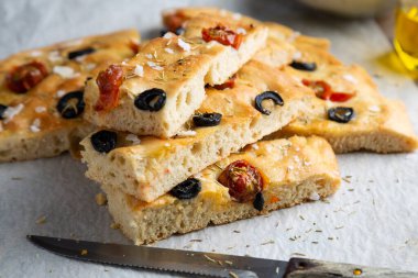  Siyah zeytinli ev yapımı Focaccia, kiraz domatesli, biberiyeli, kağıt üzerinde pullu tuz ve zeytinyağlı.