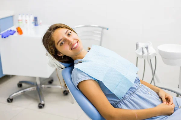 Молода жінка відвідує стоматолога і посміхається сидячи в стоматологічному кріслі . Ліцензійні Стокові Фото