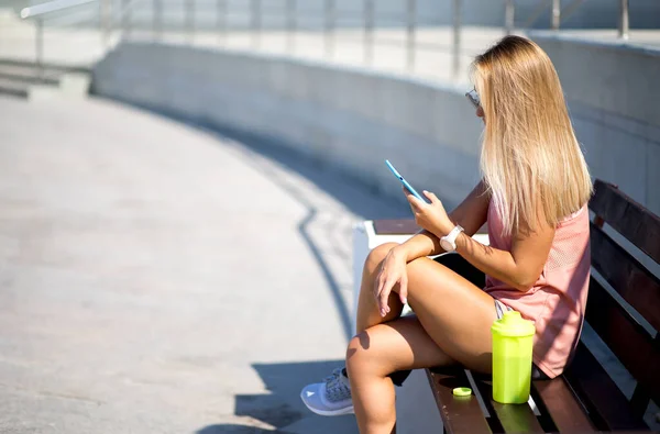Спортивна жінка дивиться на смартфон, на відкритому повітрі. Фітнес-жінка відпочиває після бігу в місті . Стокове Фото