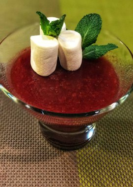 Güzel lezzetli tatlı - ahududu jöle, beyaz hatmi ve nane ile dekore edilmiş bir cam dondurma kapta bırakır.