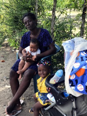 Saona, Dominicana, December 2018. Dominican family: a mother and two small dark-skinned dirty children in a fishing village.