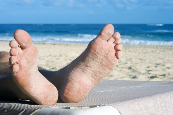 The feet of a man resting on the beach in Punta Cana, Dominican Republic, are covered in sand. Sunny day and warm ocean - a real paradise.