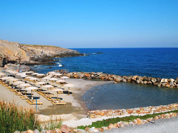 Волны ломаются на побережье. Пляж, шезлонги и зонтики, море, волны, пена на греческом курорте. Пустынный берег . — стоковое фото