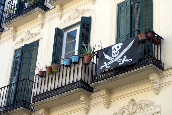     Sıva ve Ferforje balkon ile eski İspanyol evi. Balkonda çok renkli saksı ve korsan bayrağı vardır.   .         .