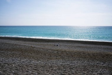 Yalnız bir adam bir ıssız çakıl plajı Cote d'Azur üzerinde. Dinlenme ve rahatlama denizin kenarında. Mavi Dalgalar güneşli sıcak günde rulo.