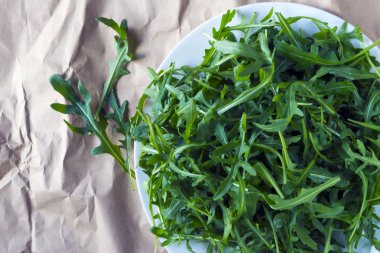 Taze roka (Eruca), turpgillerden bitki ve sadece lahana (Turpgiller) Brown'un kraft kağıt ambalaj. Rugula, Indau, Walker, Caterpillar, RoHS salata - bu yararlı Yeşiller, afrodizyak olduğunu.